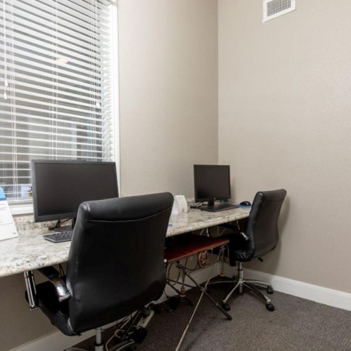 a desk with a computer and chairs